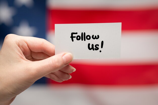 Follow us text on a card. American flag background.