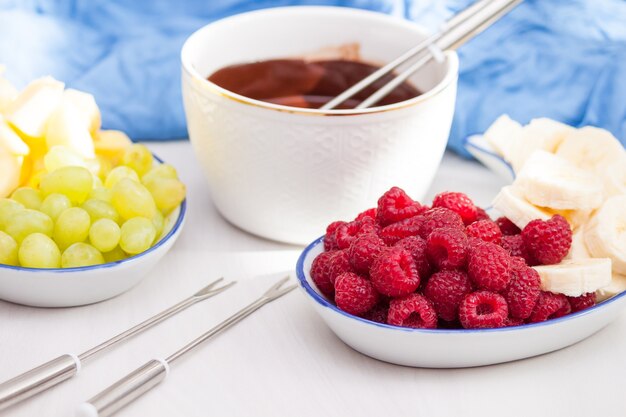 Fondue with melted chocolate, fruits and berries.