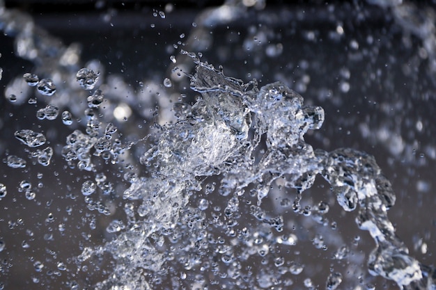 Fonteinclose-up van waterdruppeltjes donkere achtergrond