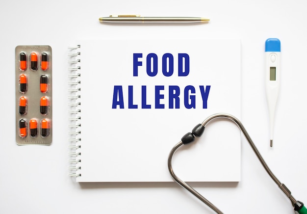 机の上にあるノートと聴診器に書かれた食物アレルギーのテキスト