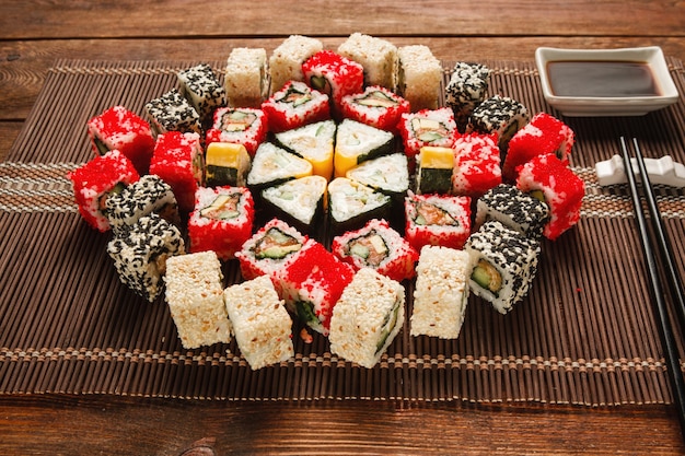 Food art, culinary masterpiece. Great set of sushi served in colorful ornament on brown straw mat, closeup. Luxury restaurant menu photo.