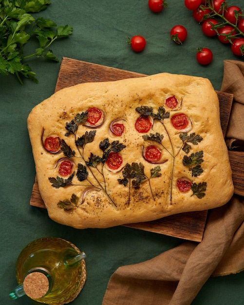 Food art focaccia flatbread met tomaten op donkergroen linnen textiel tafelkleed bovenaanzicht