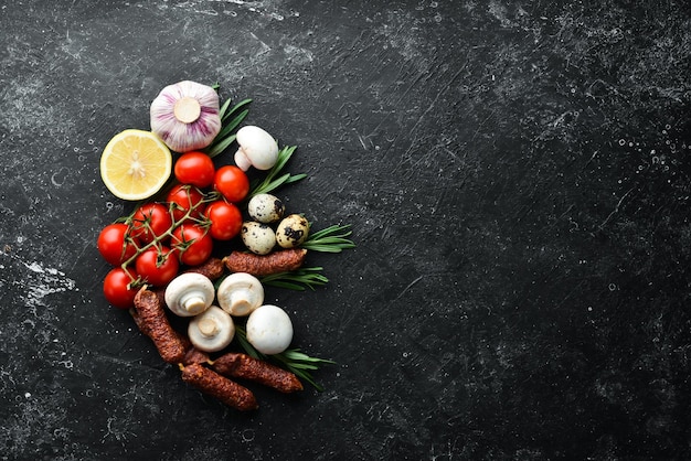 Пищевые ингредиенты для приготовления помидоров, грибов, розмарина, яиц и специй на старом фоне вид сверху