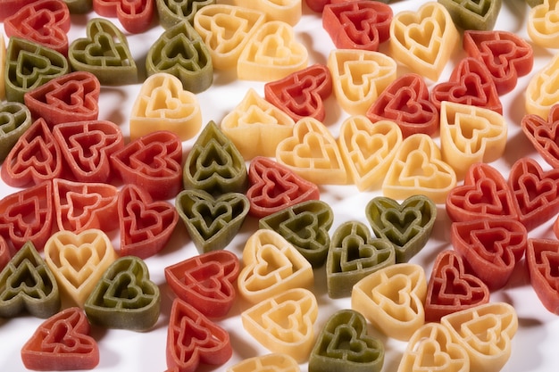 Sfondo di cibo, pasta italiana a forma di cuore di tre colori.