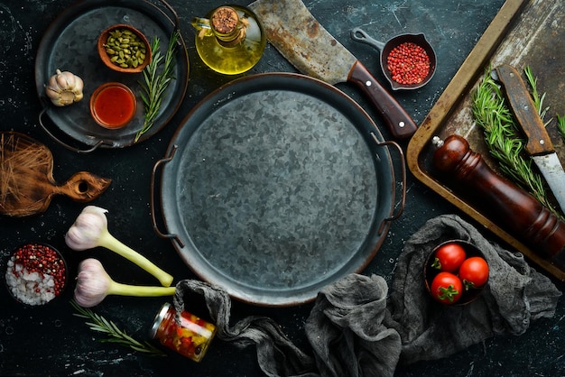 Фон еды Металлический поднос с овощами, специями и ароматными травами На фоне черного камня