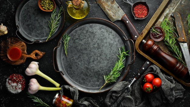 Food background Metal tray with vegetables spices and aromatic herbs On a black stone background