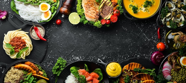 Food background pasta chicken pumpkin salad meat mushrooms vegetables On a black stone background Top view Free space for text