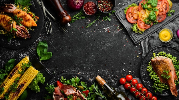 Sfondo alimentare set di piatti a base di carne di pesce e verdure su sfondo di pietra nera vista dall'alto spazio per la copia gratuito