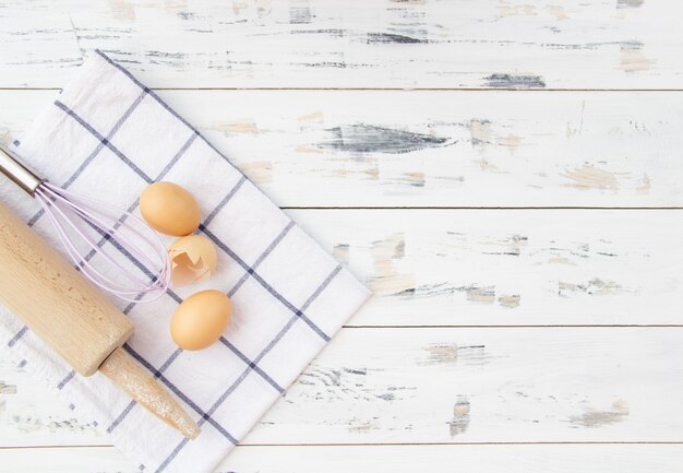 Food background with eggs, rolling pin and whisk. Top view. Free space.