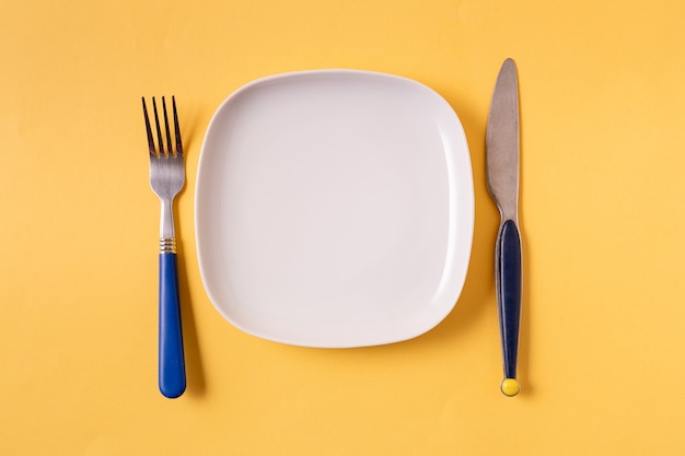 Food background with empty white plate and cutlery 