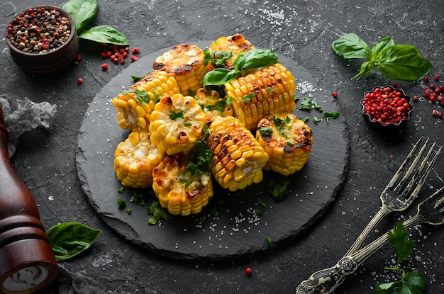 Food Baked corn with parsley and basil on a black stone plate Top view Free space for your text