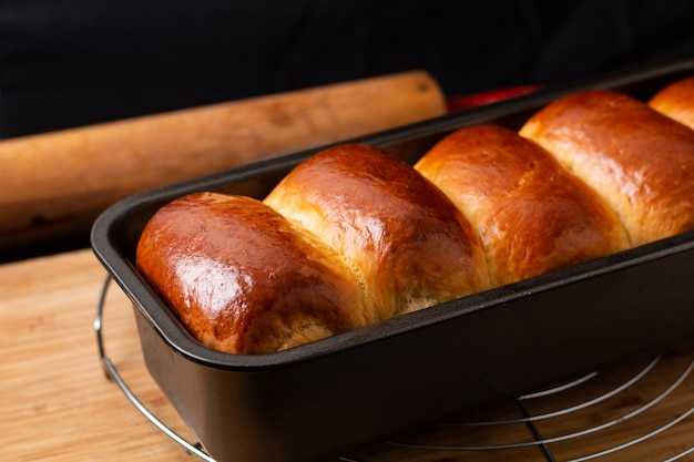 Food Baking concept Fresh baked organic homemade soft milk loaf bread in loaf pan on wooden board with copy space