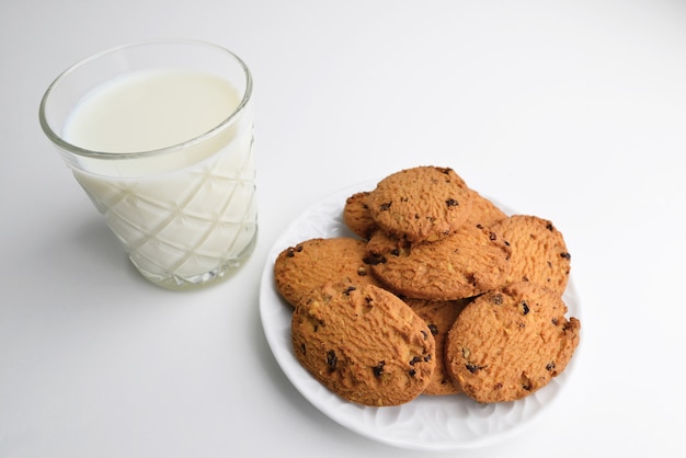 Food, baking and eating concept - close up of chocolate oatmeal cookies and milk glass on plate