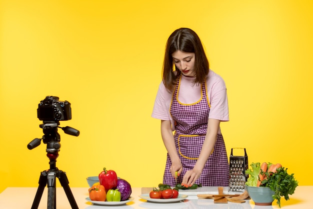 Food blogger carino adorabile chef in grembiule rosa che registra video per i social media che tagliano la cipolla