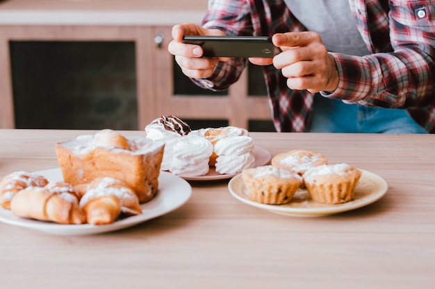 Photo food blogger. dessert. mobile photography. man with smartphone taking photos of fresh homemade pastries