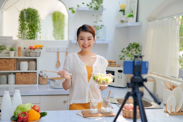 家庭の台所で電話カメラでビデオを録画する食品ブロガー