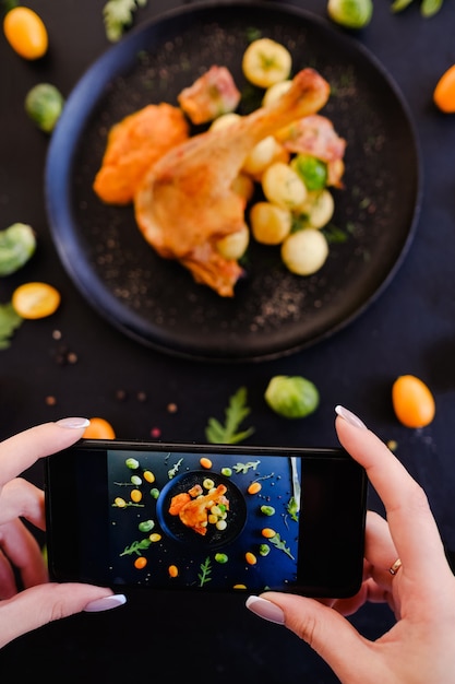 사진 음식 블로거 레스토랑 음식 스마트 폰 사진 개념. 소셜 네트워크 의존성. 맛있는 닭다리 요리.