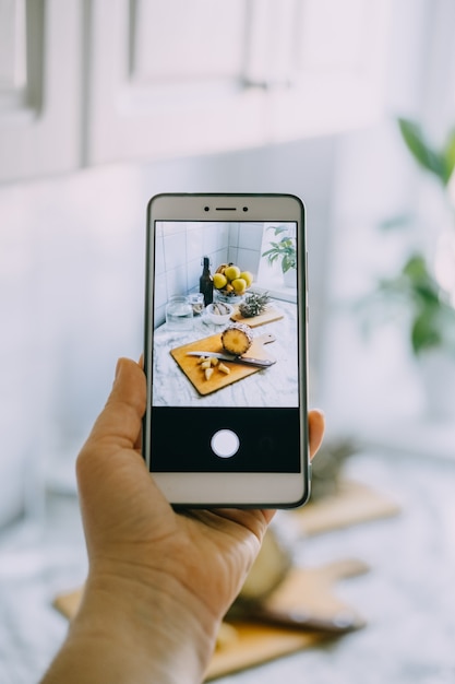 Food blogger takes photo on smartphone for social networks female hand holding cell phone with photo