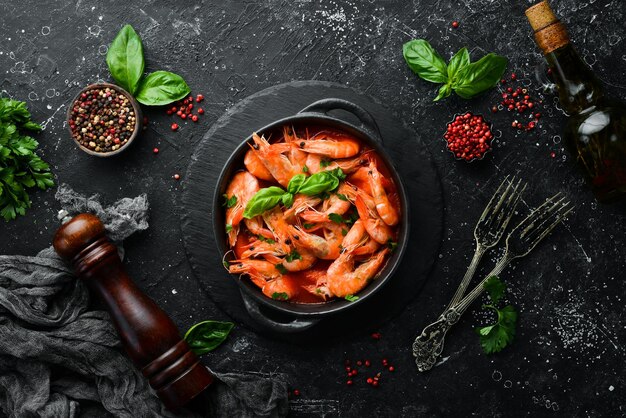 Food Boiled shrimp in tomato sauce with basil on a black stone plate Top view Free space for your text