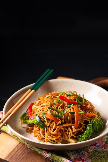 Photo food concept asian egg noodles stir fry in ceramic bowl on wooden board with copy space