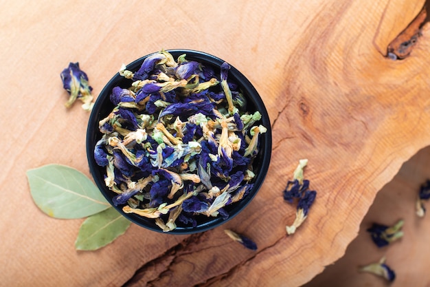 Il concetto asciutto del fiore del pisello di farfalla dell'alimento per fa la tisana in tazza di ceramica sul bordo di legno