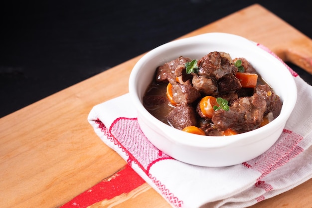 Food concept French red wine beef stew bourguignon on wooden board with copy space