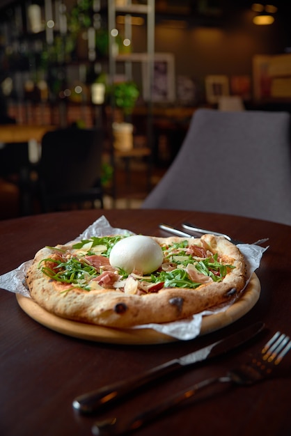 Food concept. Fresh original Italian Pizza with burrata, prosciutto and arugula.