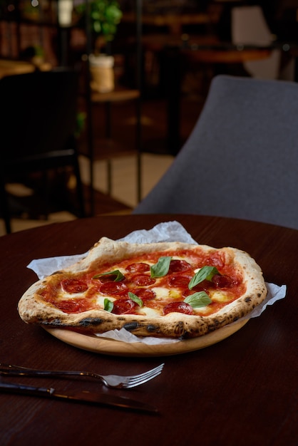 Food concept. Fresh original Italian pizza on a wooden board in Italian pizzeria or restaurant.