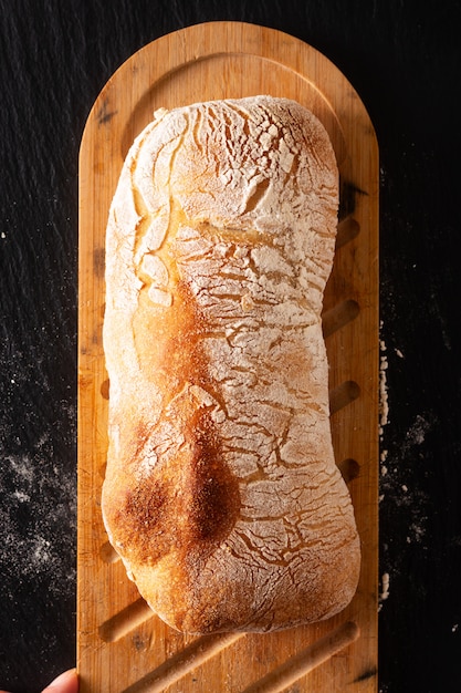 Foto pane italiano di ciabatta della pasta di lievito di stile italiano artigianale casalingo di concetto dell'alimento sul bordo nero dell'ardesia con lo spazio della copia