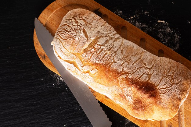 Foto pane italiano di ciabatta della pasta di lievito di stile italiano artigianale casalingo di concetto dell'alimento sul bordo nero dell'ardesia con lo spazio della copia