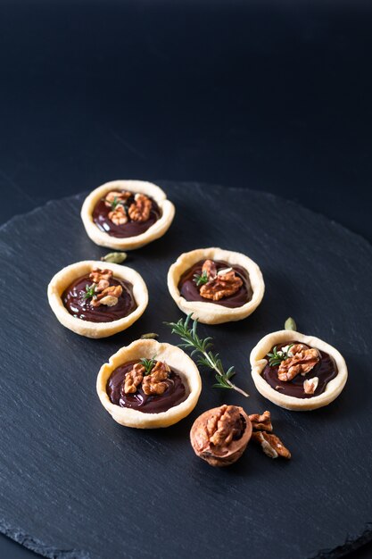 Food concept Homemade rustic organic mini chocolate and walnuts tarts on black slate stone plate with copy space