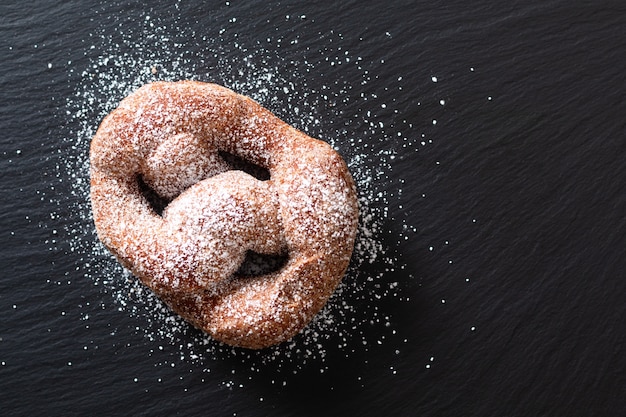 Concetto di cibo singolo beignet lievito francese ciambella fritti fritti pasticceria sul bordo nero ardesia