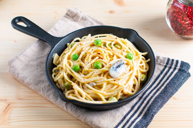 Food concept spaghetti creamy white sauce in cast-iron skillet pan on wood background