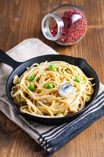 Salsa bianca cremosa degli spaghetti di concetto dell'alimento in padella della padella della ghisa su fondo di legno