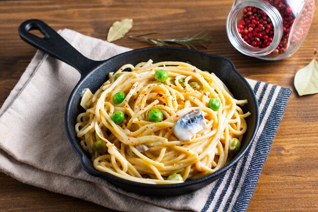 Food concept spaghetti creamy white sauce in cast-iron skillet pan on wood background