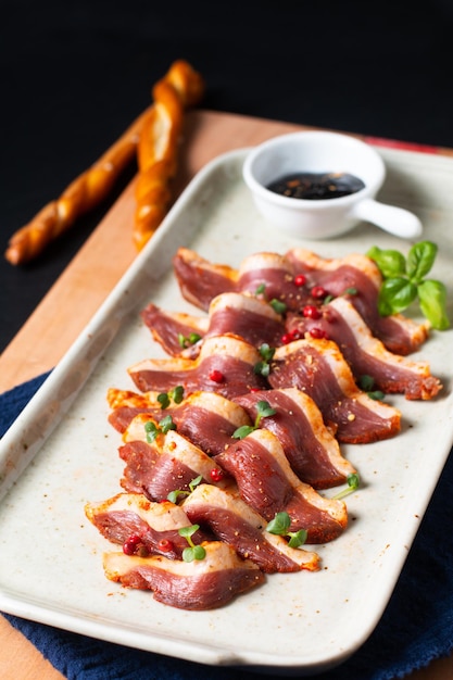 Food concept Spicy Smoked duck breast in ceramic plate on wooden board with copy space