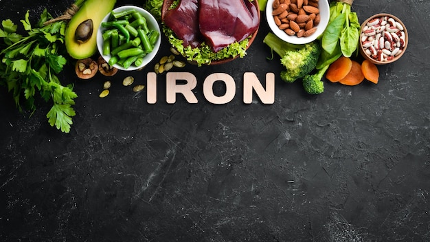 Food containing natural iron Fe Liver avocado broccoli spinach parsley beans nuts on a black stone background Top view