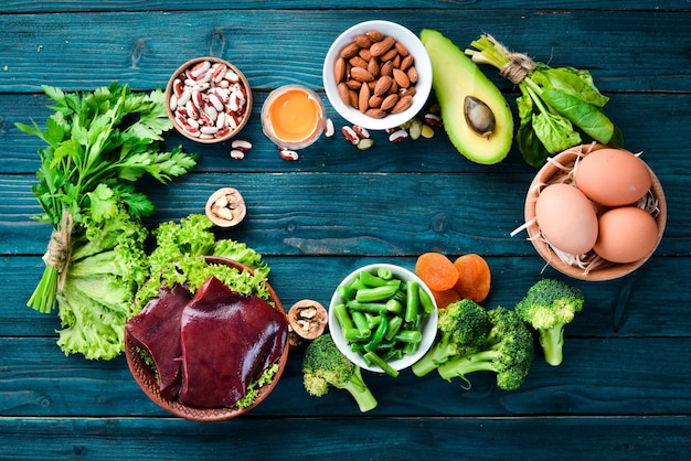 Photo food containing natural iron fe liver avocado broccoli spinach parsley beans nuts on a blue background top view