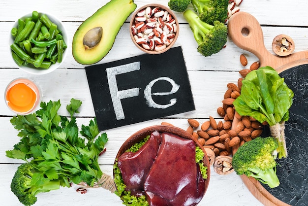 Food containing natural iron Fe Liver avocado broccoli spinach parsley beans nuts on a white wooden background Top view