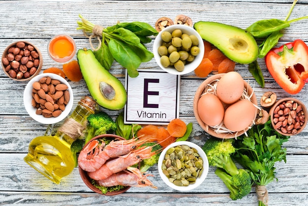 Food containing natural vitamin E Spinach parsley shrimp pumpkin seeds eggs avocados broccoli Top view On a white wooden background