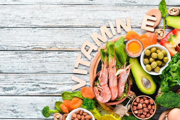 Food containing natural vitamin E Spinach parsley shrimp pumpkin seeds eggs avocados broccoli Top view On a white wooden background