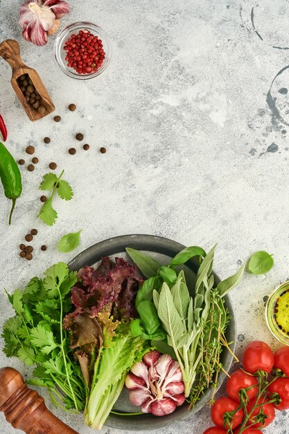 Food cooking background. Fresh saffron, garlic, cilantro, basil, cherry tomatoes, peppers and olive oil, spices herbs and vegetables at light grey slate table. Food ingredients top view.