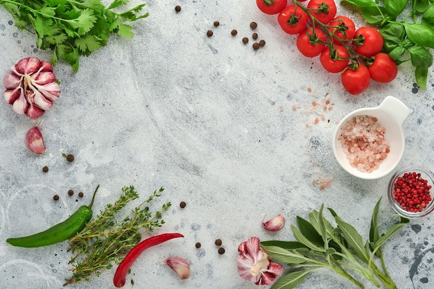 Food cooking background. Fresh saffron, garlic, cilantro, basil, cherry tomatoes, peppers and olive oil, spices herbs and vegetables at light grey slate table. Food ingredients top view.