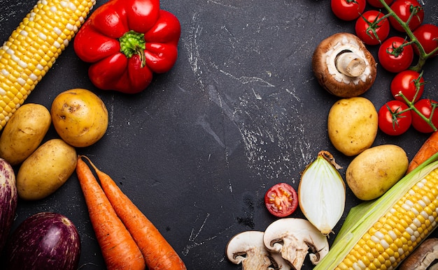 Fondo di cottura del cibo con ingredienti, verdure crude fresche assortite su sfondo di pietra scura nera dall'alto