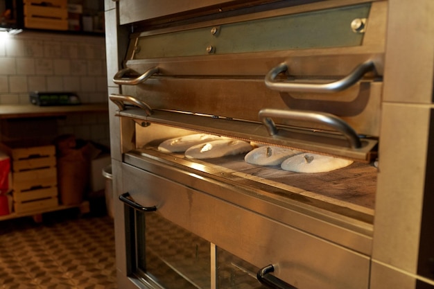 Foto cibo, cottura e concetto di cottura - pasta di pane al lievito in forno nella cucina della panetteria