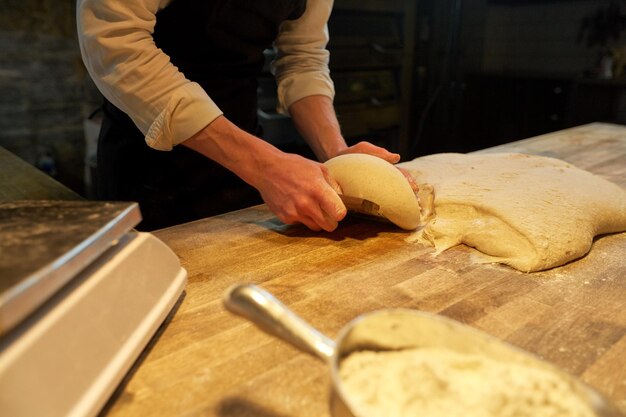 food cooking, baking and people concept - chef or baker portioning dough with bench cutter at bakery