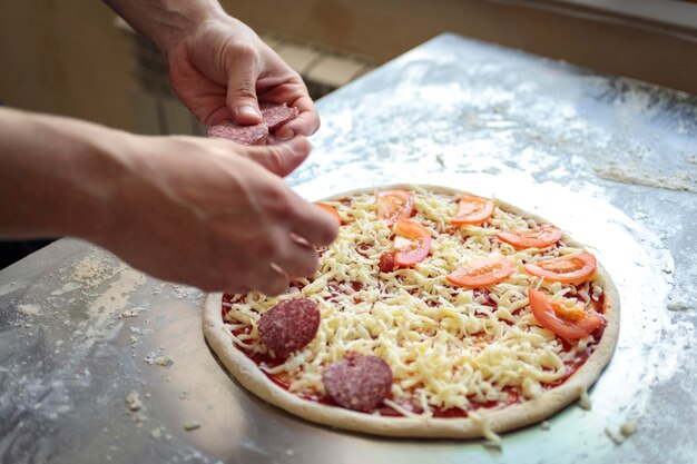 Foto cucina alimentare concetto culinario e di persone - cuoco o fornaio a mano con la pizza sulla buccia in pizzeria