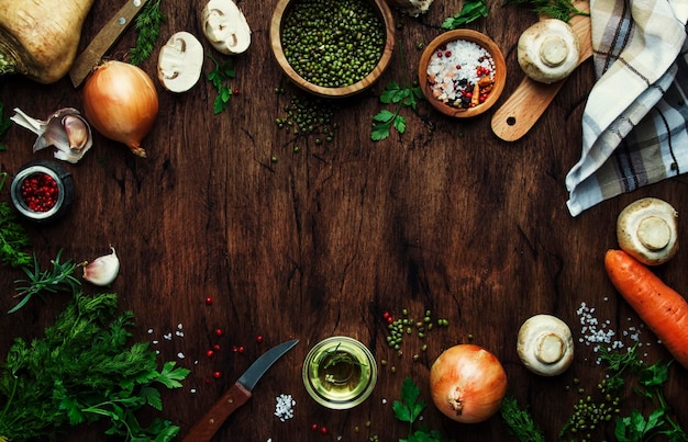 Food cooking frame background Ingredients for prepare green lentils with vegetables spices and herbs wooden kitchen table background place for text Vegan or vegetarian food oncept Top view flat lay