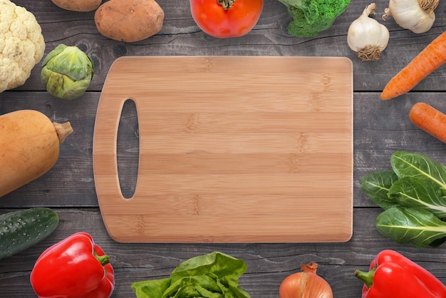 Food cutting board surrounded with vegetables on black wooden desk Vintage flat lay top view