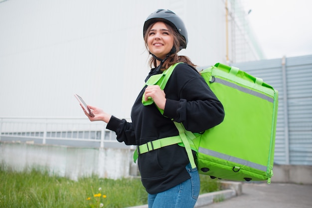 Food delivery concept. The food delivery woman has a green fridge backpack. She wants to deliver faster and get to customers. She brought us food